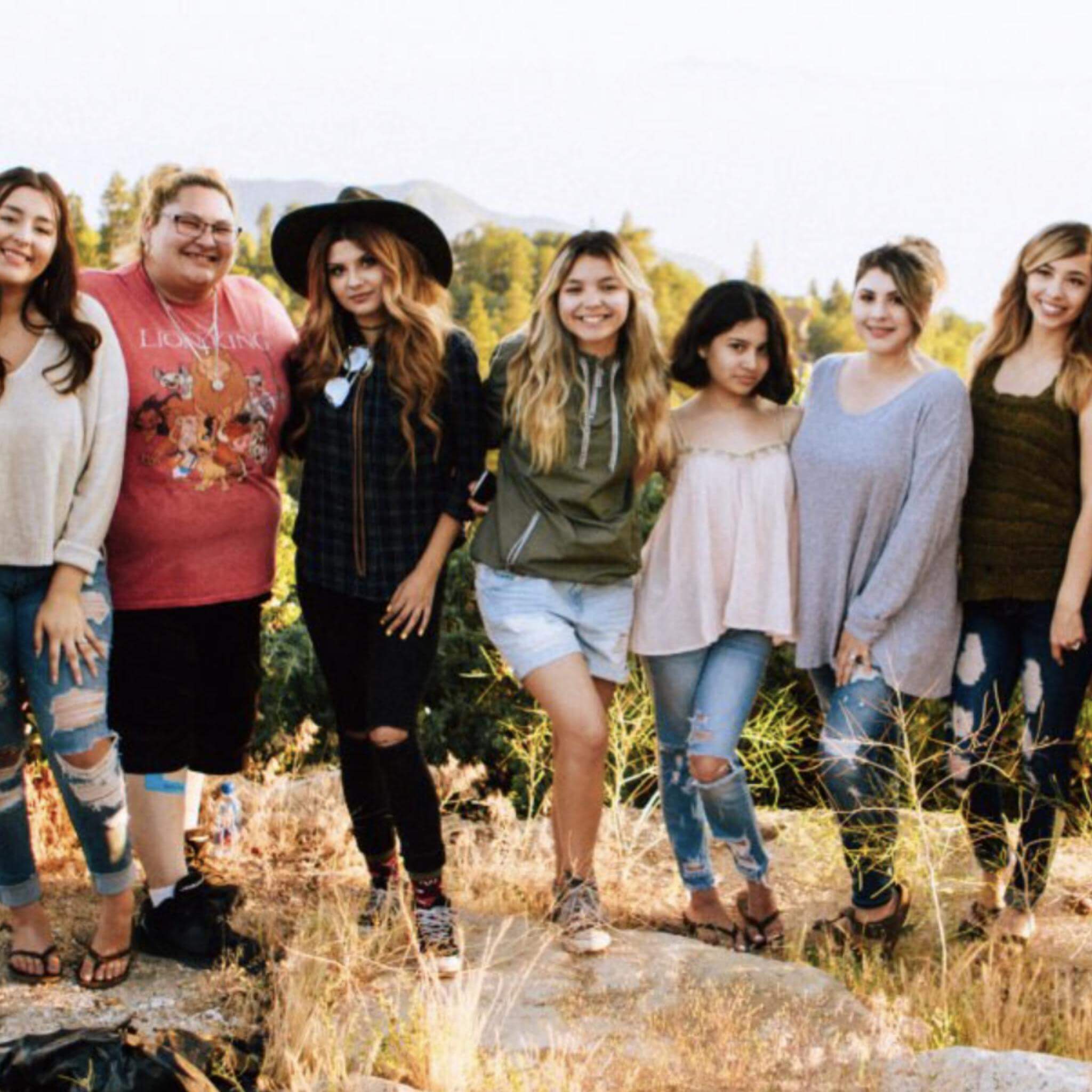 Abingdon Co. Image displays group of diverse young women standing outside in a row in the outdoors smiling