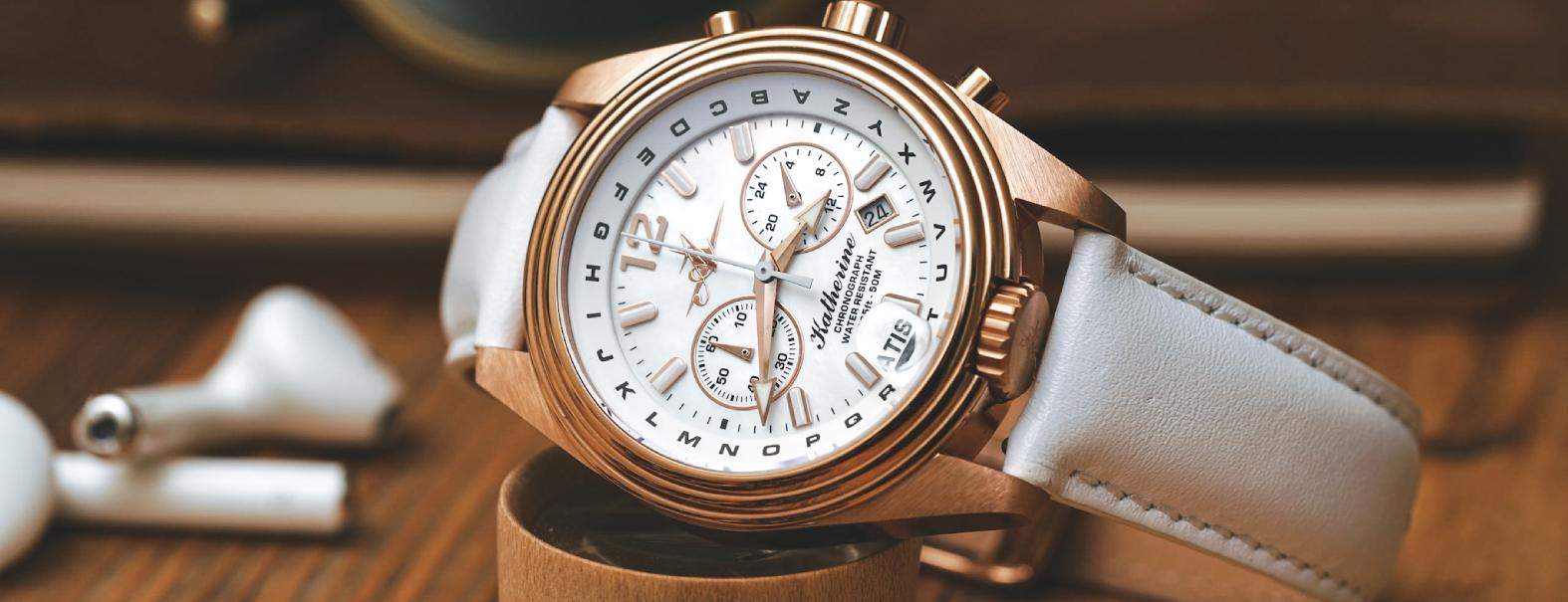Abingdon Co. A image displaying  Katherine First Class with 24k rose gold mother of pearl analog watch with white leather strap side front view on wrist. 24k rose gold watch head that has a white leather band and a white dial tilted on its side on the left side in a display motion
