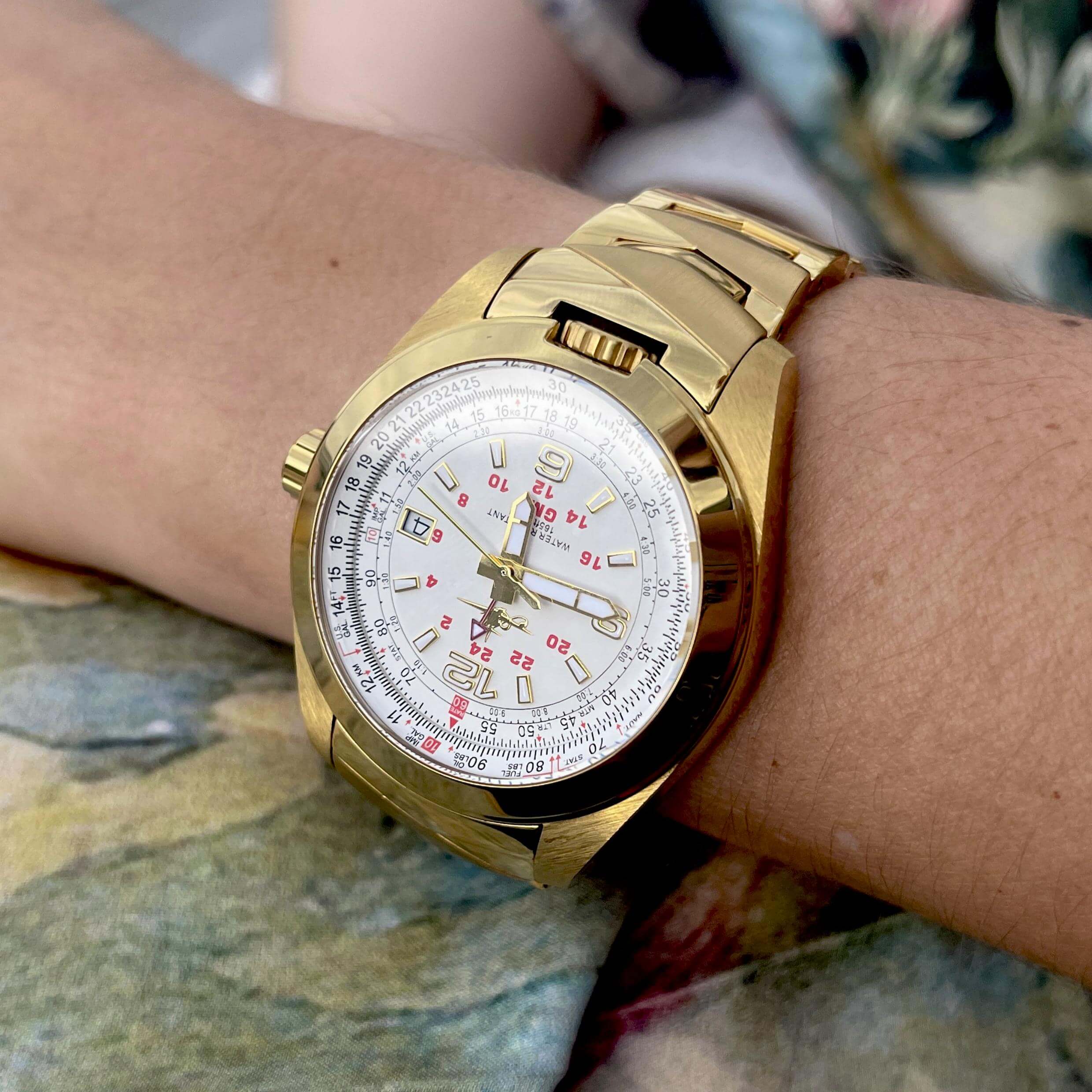 Amelia watch in Crowning Gold on wrist on a young black woman. Pilot watches like the Amelia are built for pilots and aviation industry. Designed with a flight computer, also called an E6B or slide rule, it calculates currency and fuel consumption. GMT