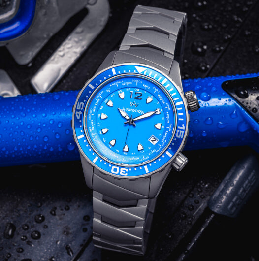 Abingdon Co. Image displays Bahama Blue Marina watch with a sandblasted titanium grey band sitting on the top of a snorkel and scuba tank.