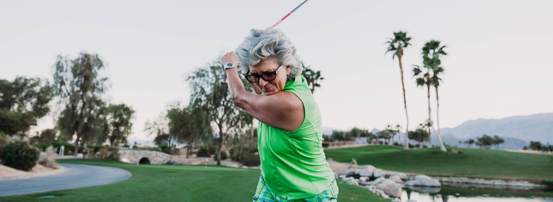 Captain Jan Anderson wearing a Green tank top and in a position ready to hit a a gold ball at a gold course with a Abingdon watch on her left wrist