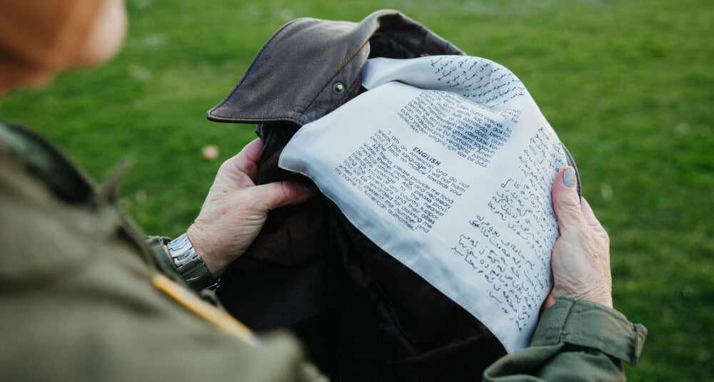 Abingdon Co image of a woman holding a jacket over a message sewn on the inside in an outdoor setting.