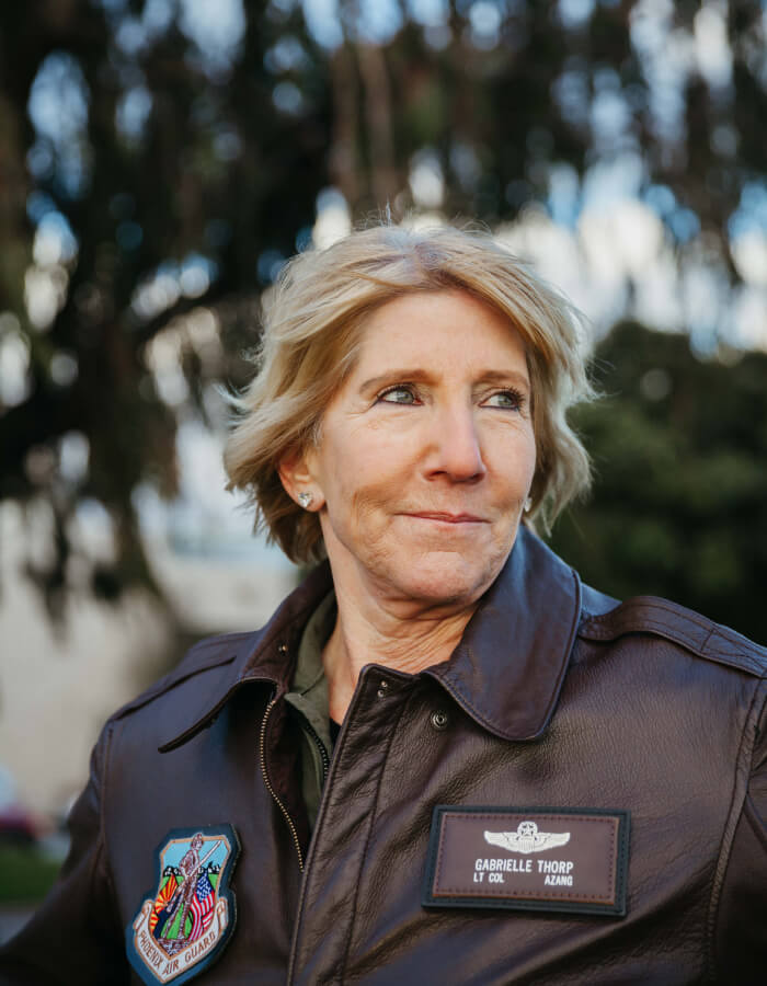 Abingdon Co. image of an older blonde woman with medium length blonde hair wearing a jacket with a name tag and patch outdoors