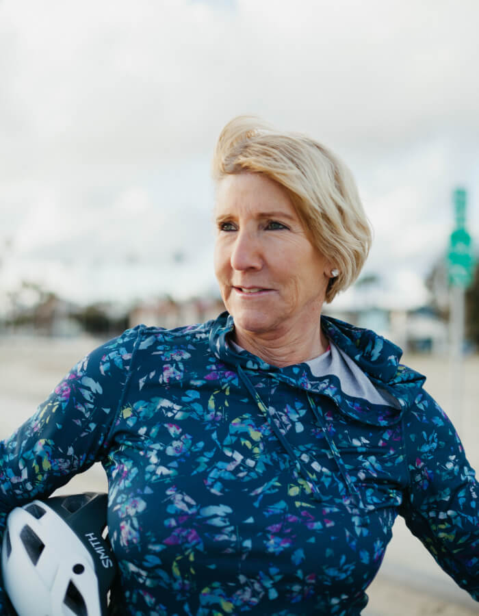 Abingdon Co. image of a woman in a blue floral athletic gear holding a helmet outdoors